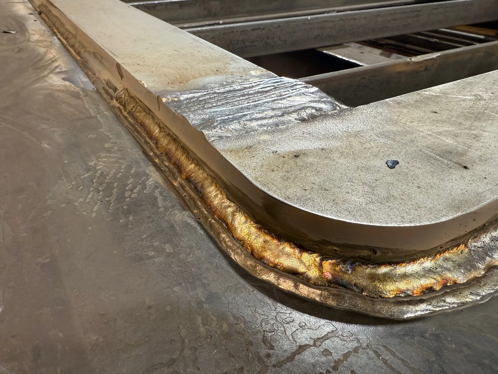 A rainbow-temper weld carried continuously around a door corner - one clean pass for a water-tight seal.