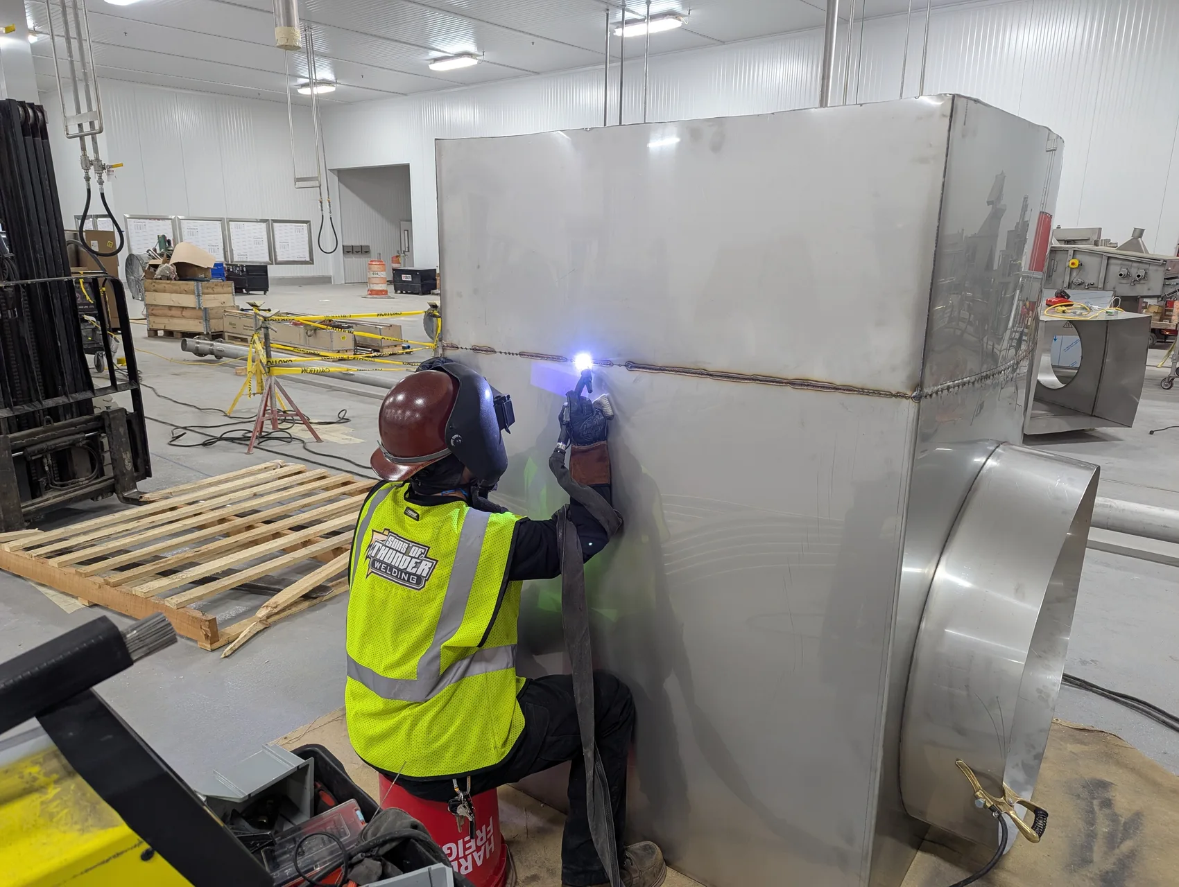 Running a seam on the 66-inch square stainless duct in full PPE - the centerpiece of the fryer exhaust.