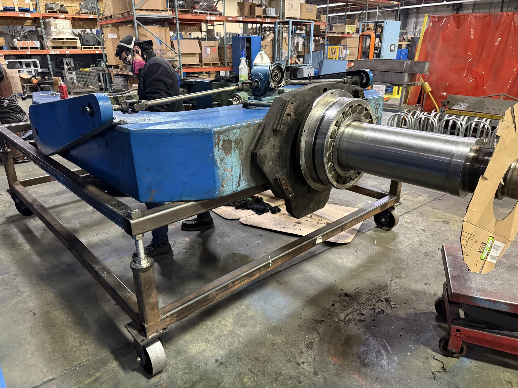 Repaired blue Rotator 66 cradle weldment with a machined steel shaft strapped to a flatbed truck, ready to return to service, by Sons of Thunder Welding