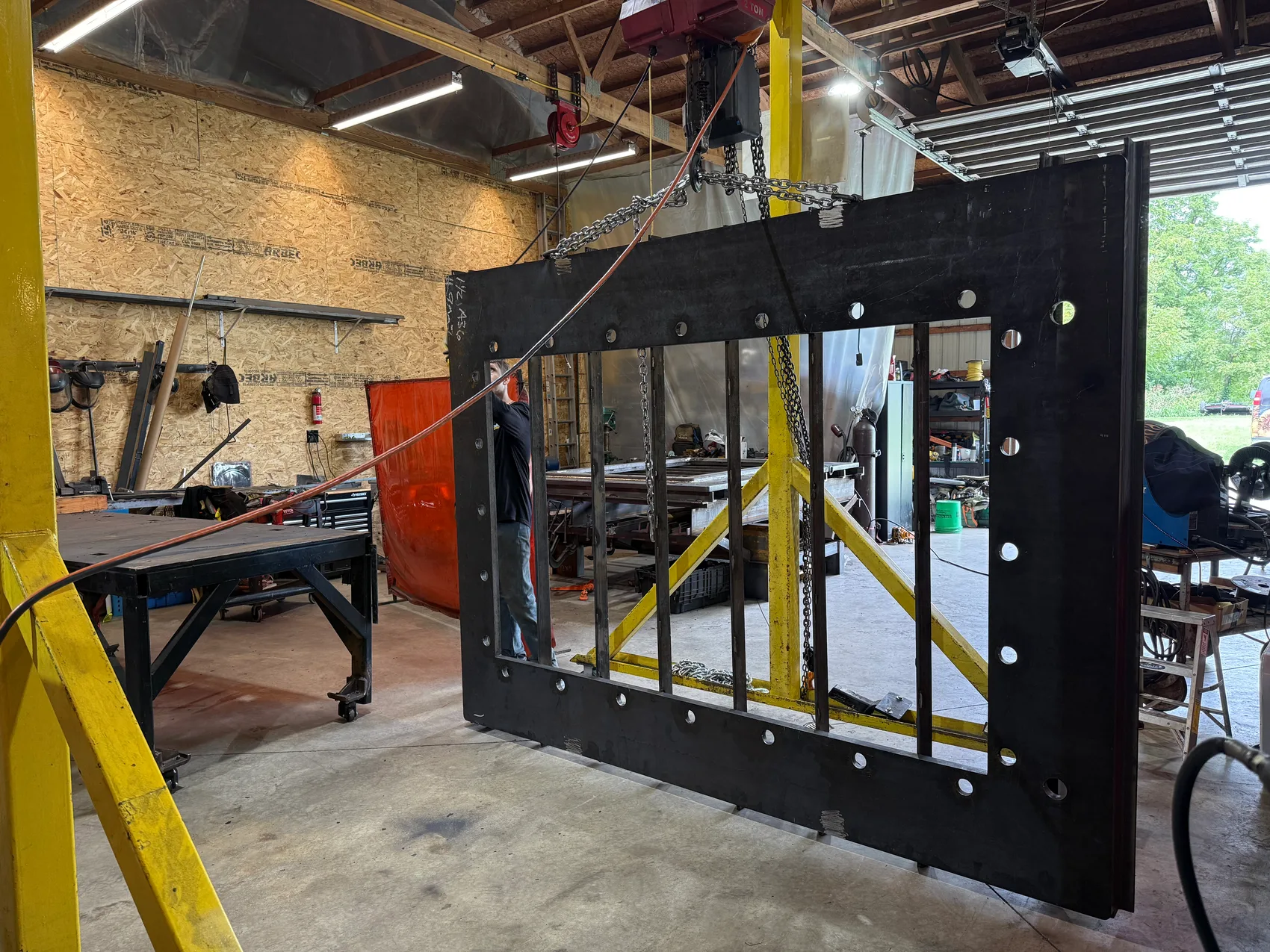 Massive steel door weldment rigged on the shop gantry