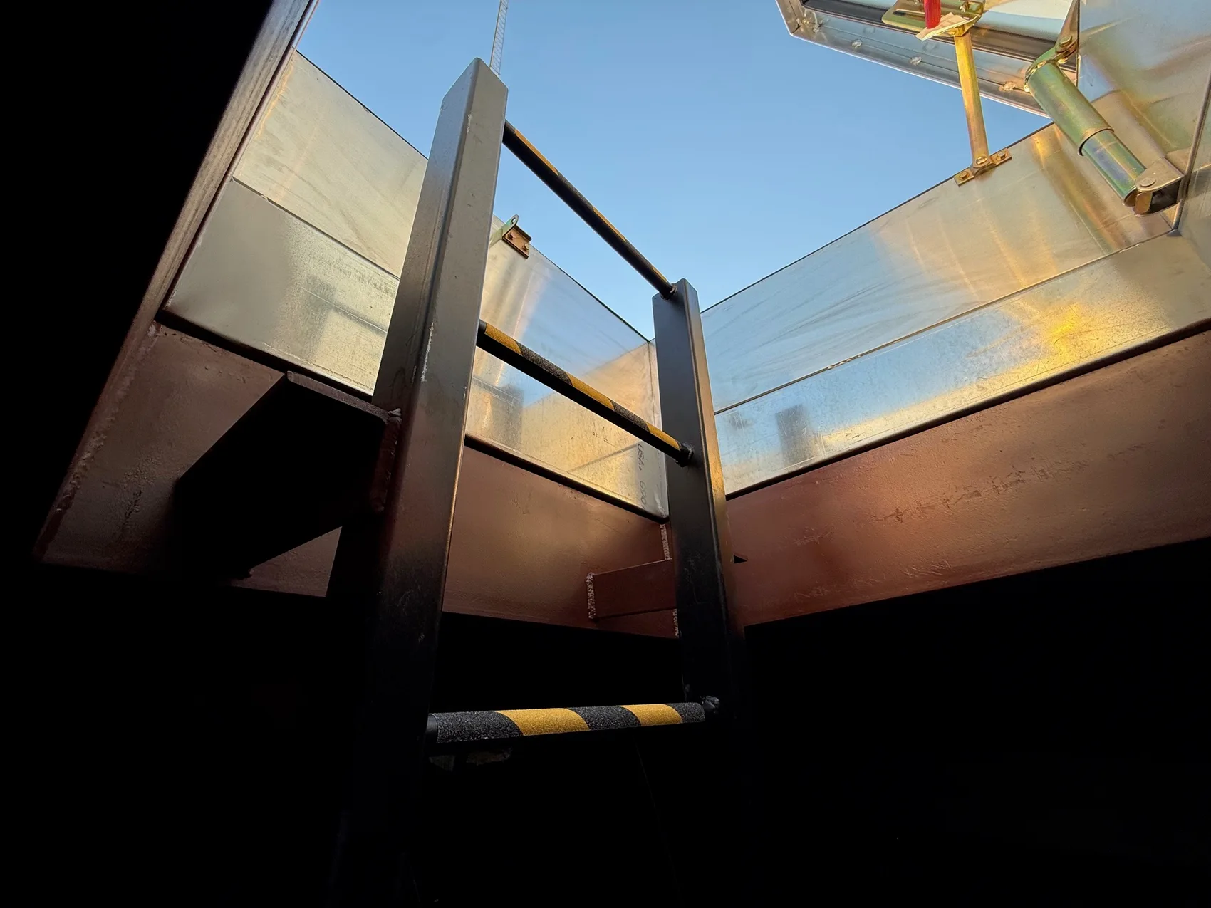 Steel ladder rising to the open roof hatch