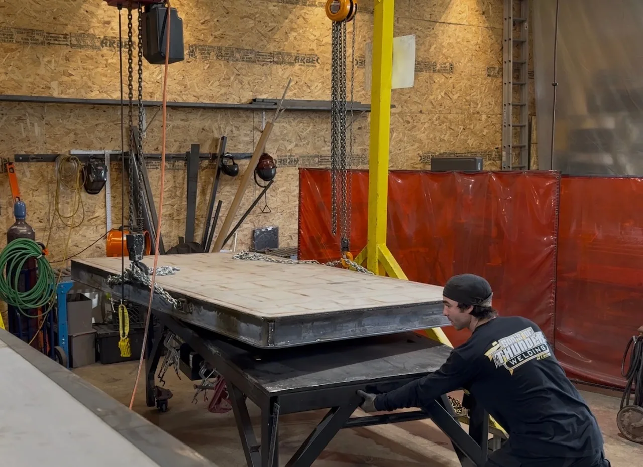 Crew rigging a large table weldment with hoists