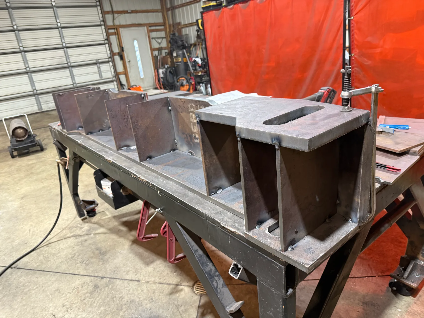 A row of slotted steel box-housing weldments