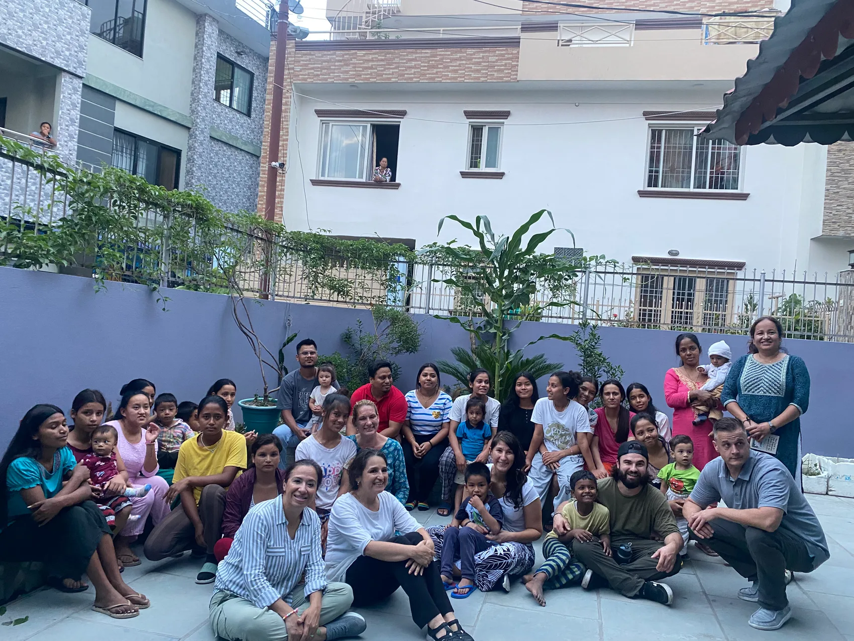 Sons of Thunder mission team with local mothers and children seated in a courtyard in Nepal