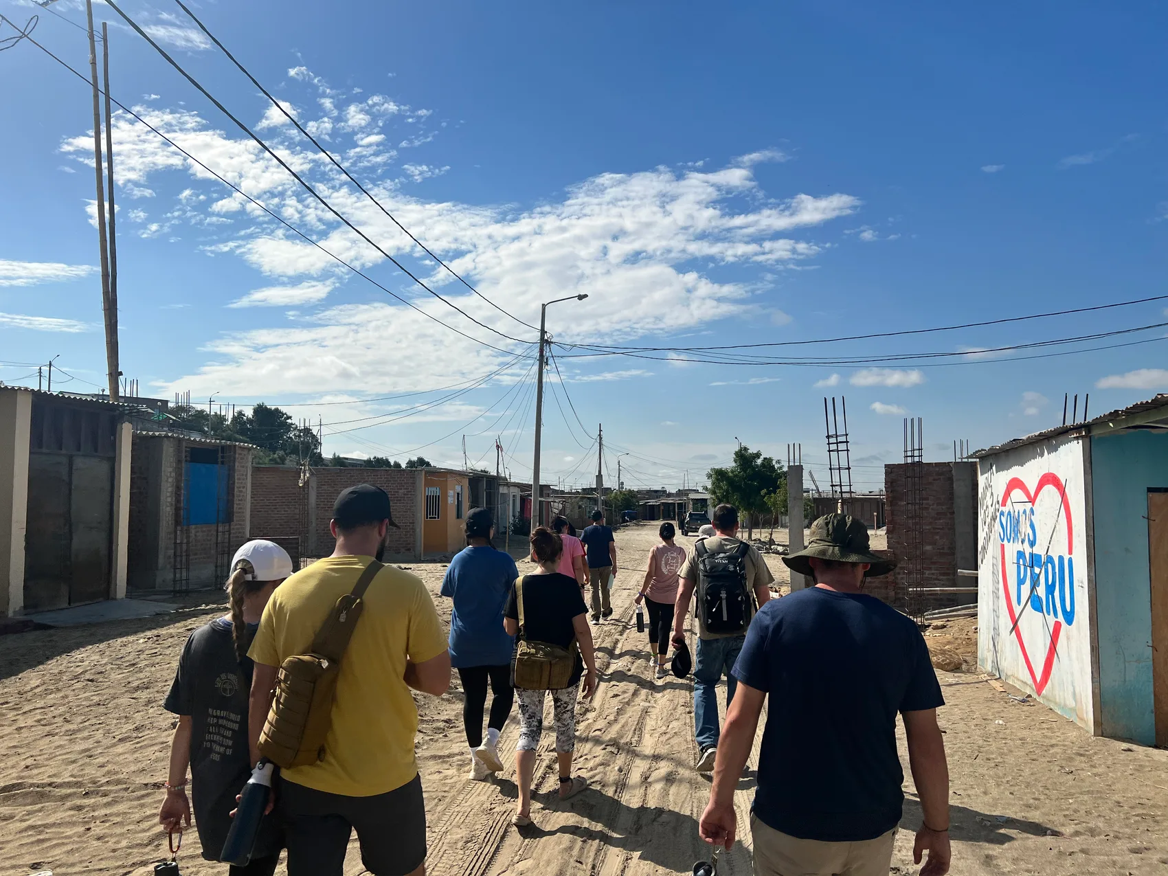 Sons of Thunder team walking through a village in Peru past a Somos Perú heart mural