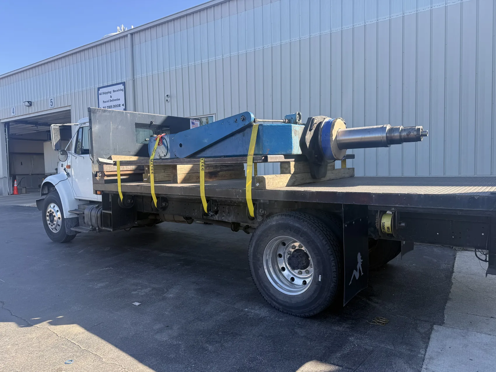 Repaired blue Rotator 66 cradle weldment with a machined steel shaft strapped to a flatbed truck, ready to return to service, by Sons of Thunder Welding