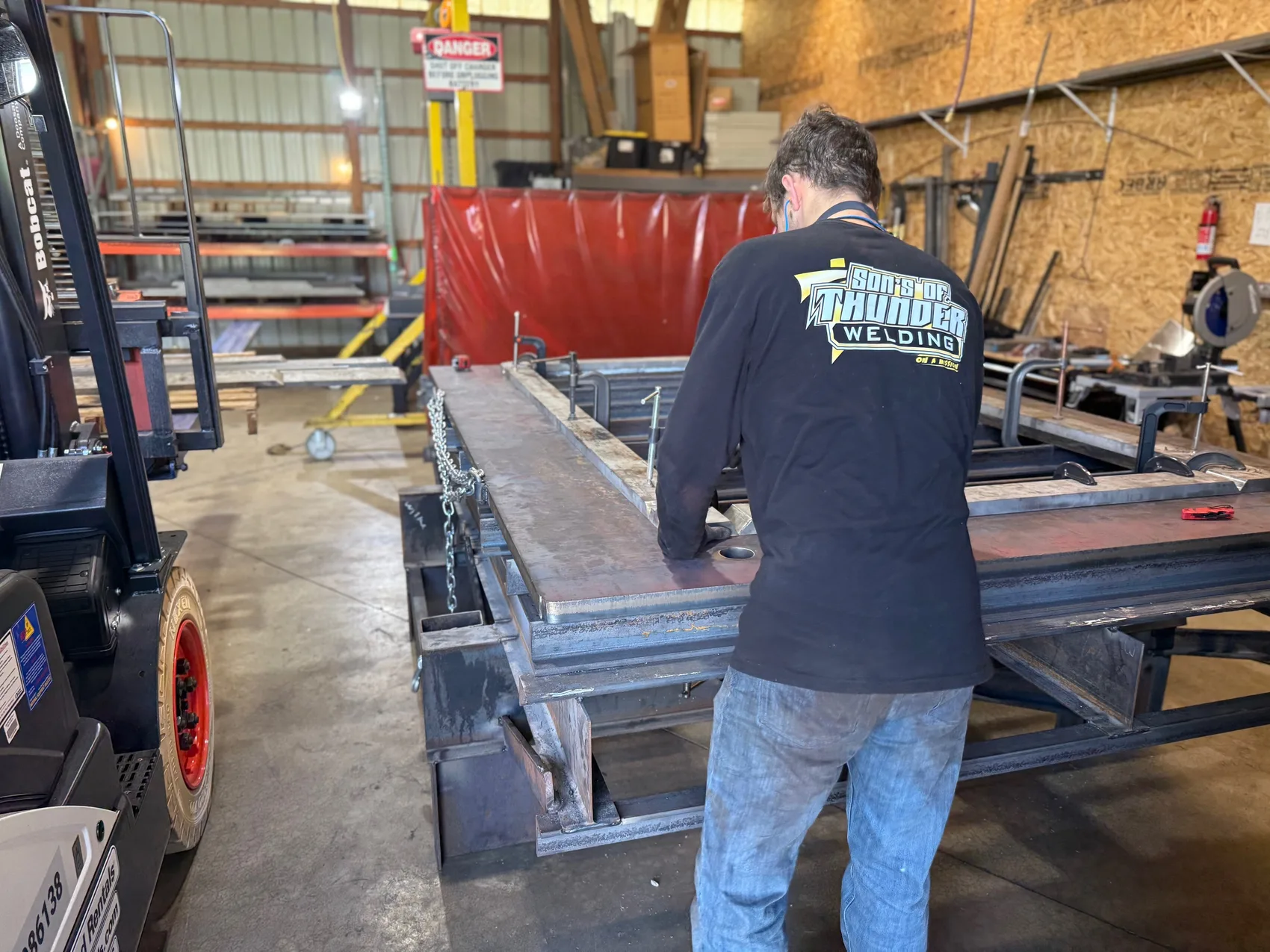 Sons of Thunder Welding crew member fabricating a large black steel weldment in the shop