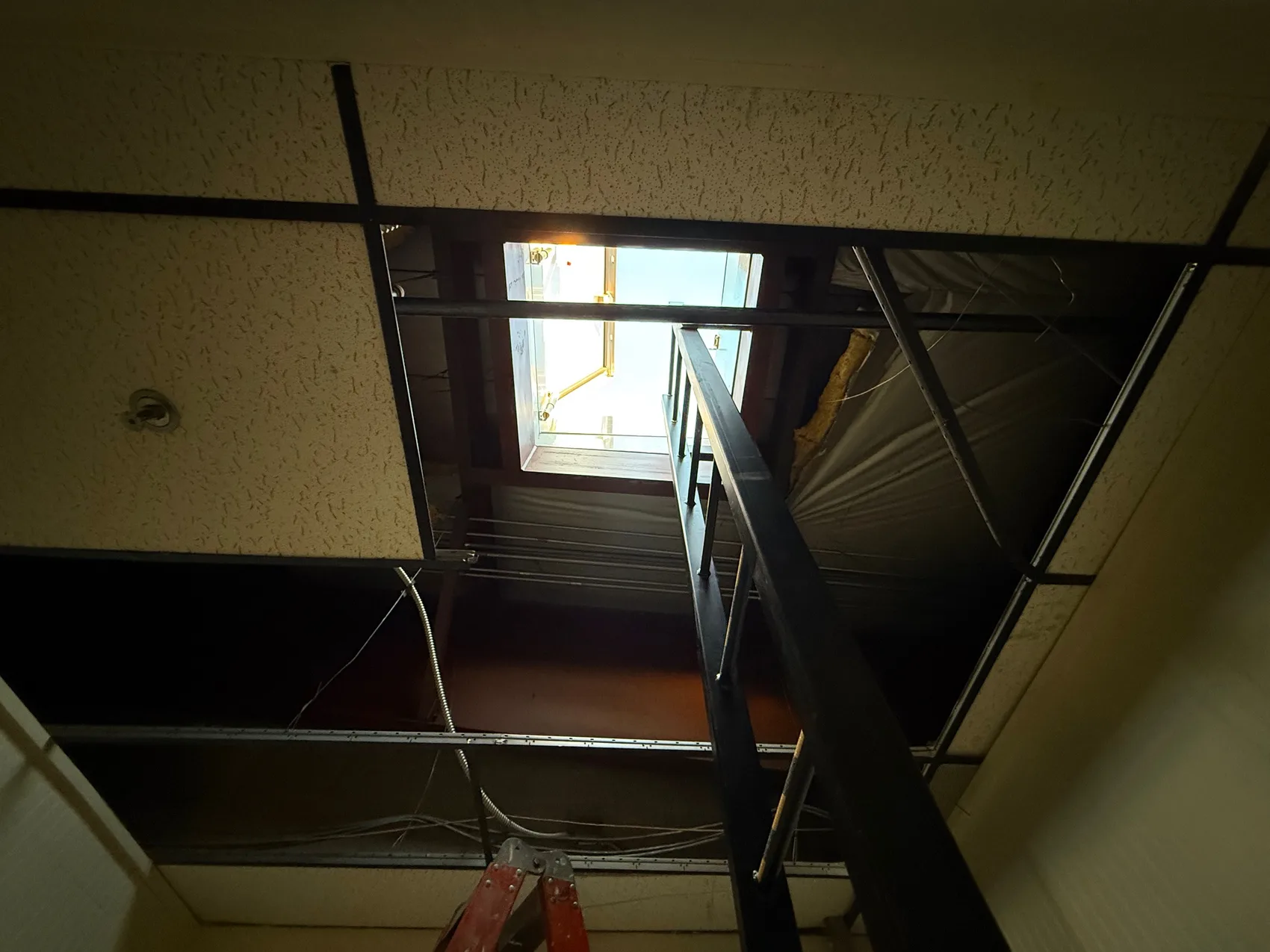 Looking up through the new roof penetration at the installed hatch and internal steel ship's ladder, daylight pouring in.