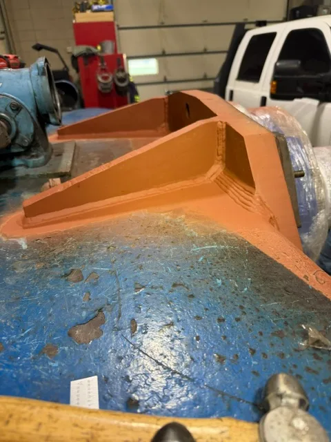 A repaired cradle bracket back in primer - gusseted, rebuilt, and staged for reassembly.