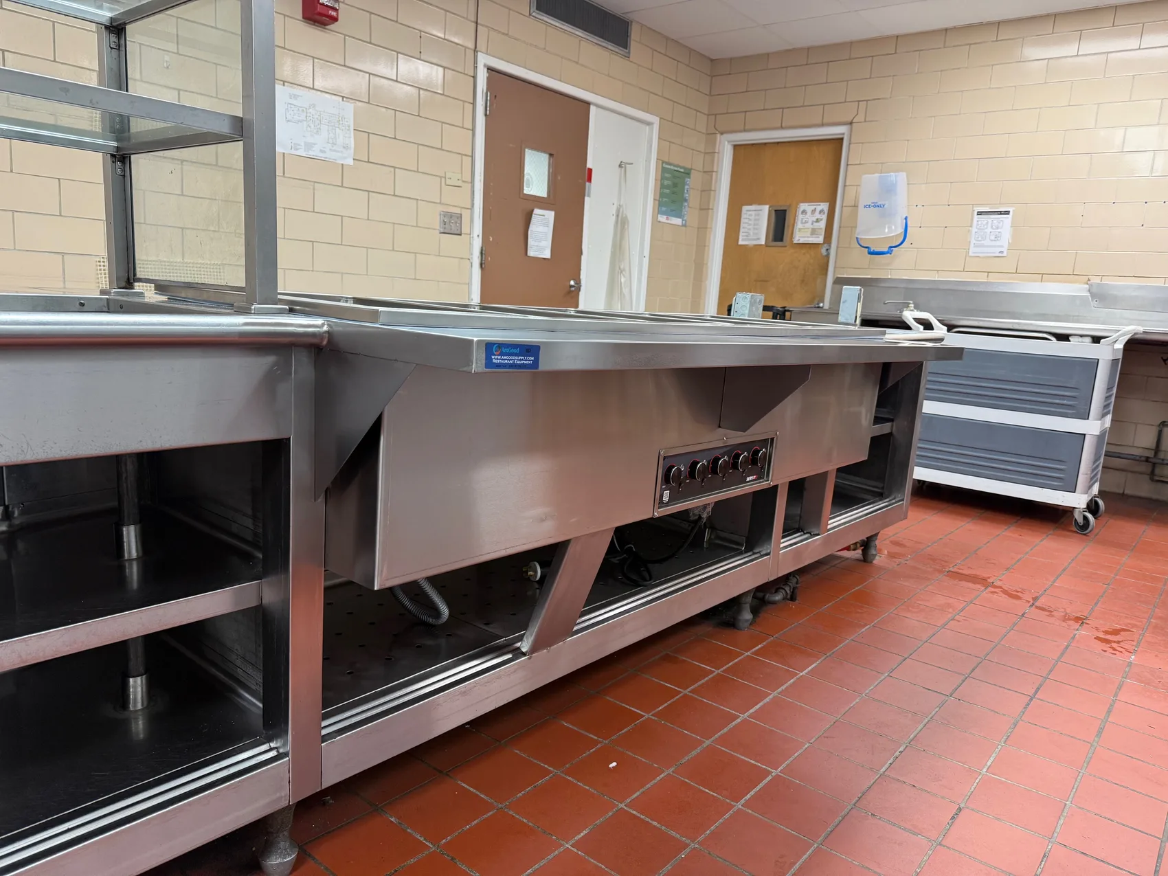 Finished stainless steel steam-well serving counter with sneeze guard in an institutional kitchen