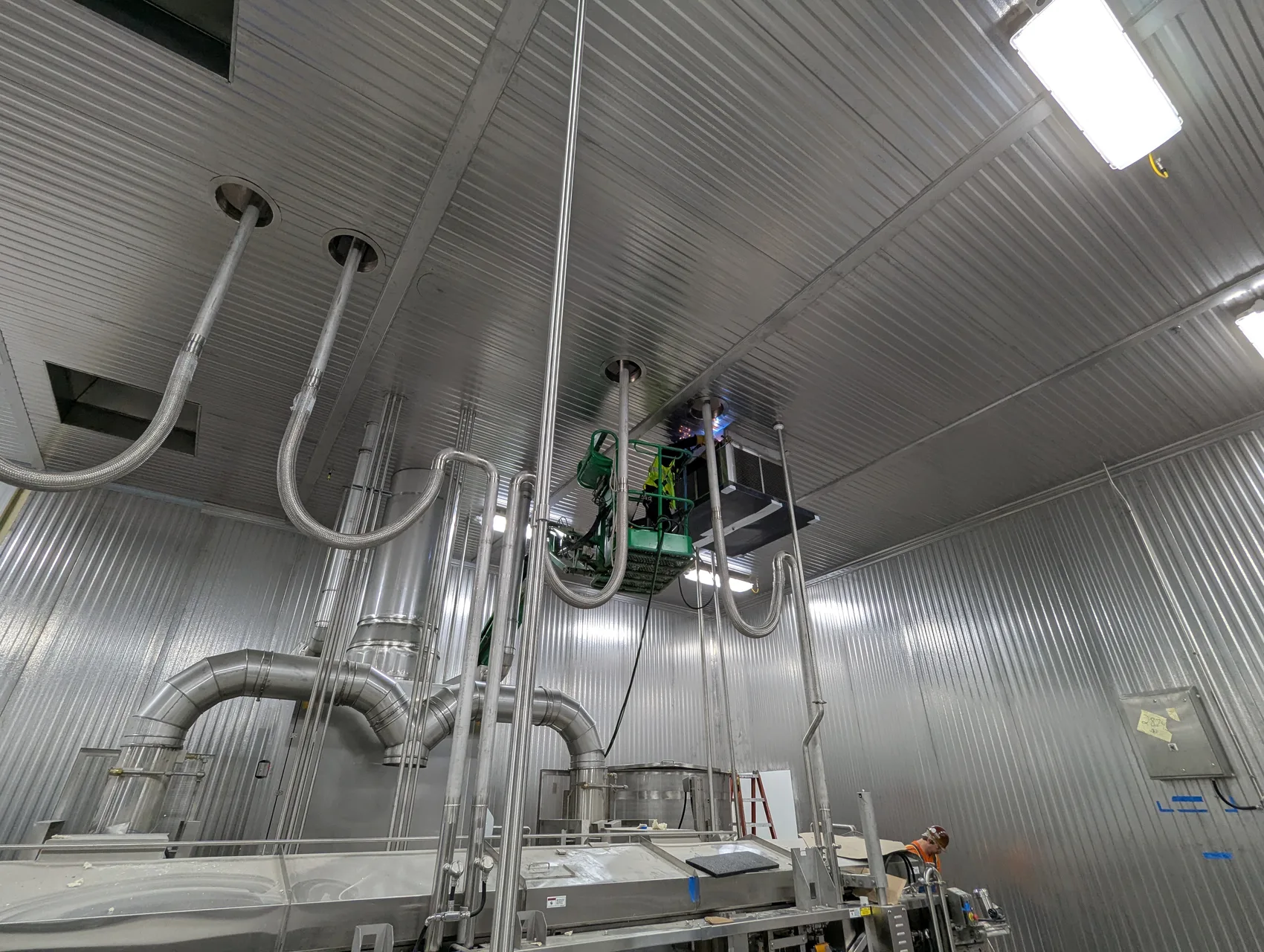 Field welder on a lift installing stainless exhaust ductwork in a food plant by Sons of Thunder Welding